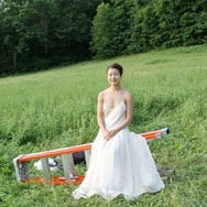 Dancer sitting on ladder in the middle of a field